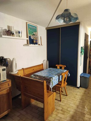 A bedroom with a bed, a desk, a chair, a wardrobe, and a poster on the wall. - Lagon Azur – Charmant studio avec piscine proche plage (Le Grau-du-Roi)