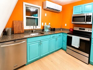 Une cuisine avec des meubles de couleur turquoise, un lave-vaisselle, un four à micro-ondes et un four traditionnel.