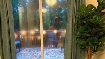 A room with a sliding glass door leading to an outdoor patio, a potted plant, and a patterned floor.