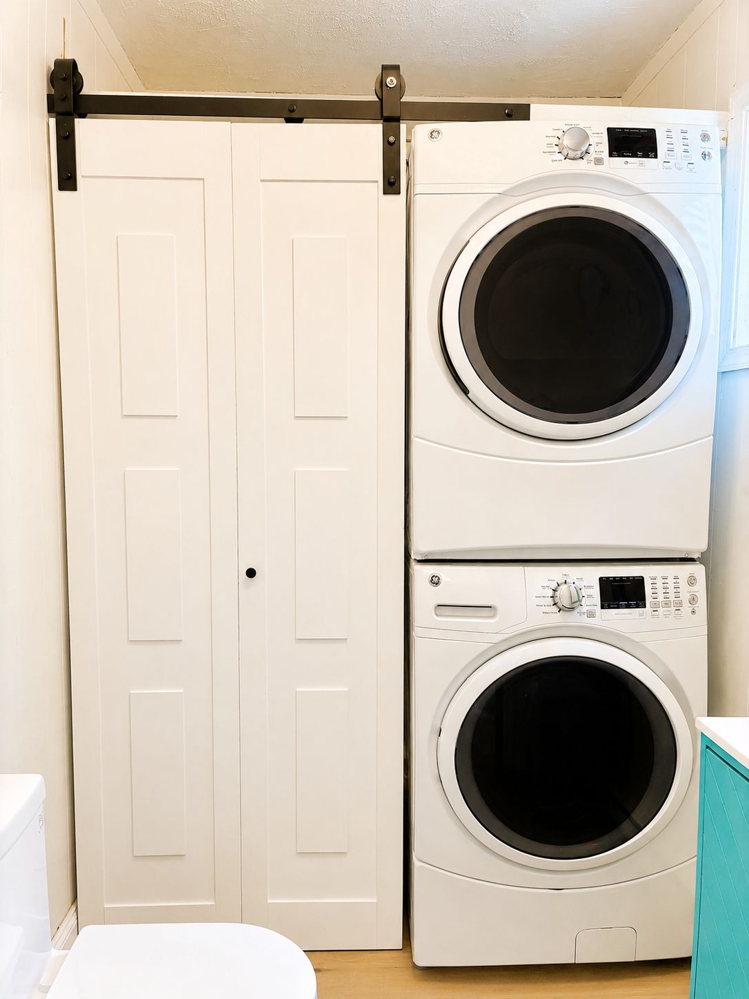 A laundry room with two stacked front-loading washing machines and a sliding door closet.
