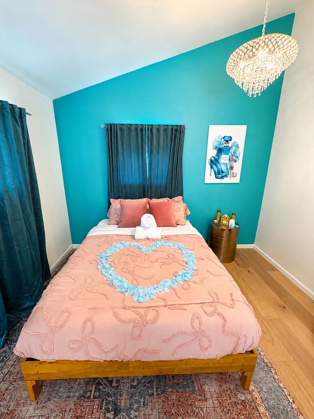 Un dormitorio con cama, decoración en forma de corazón sobre el edredón, una araña y una pared con detalles azules.