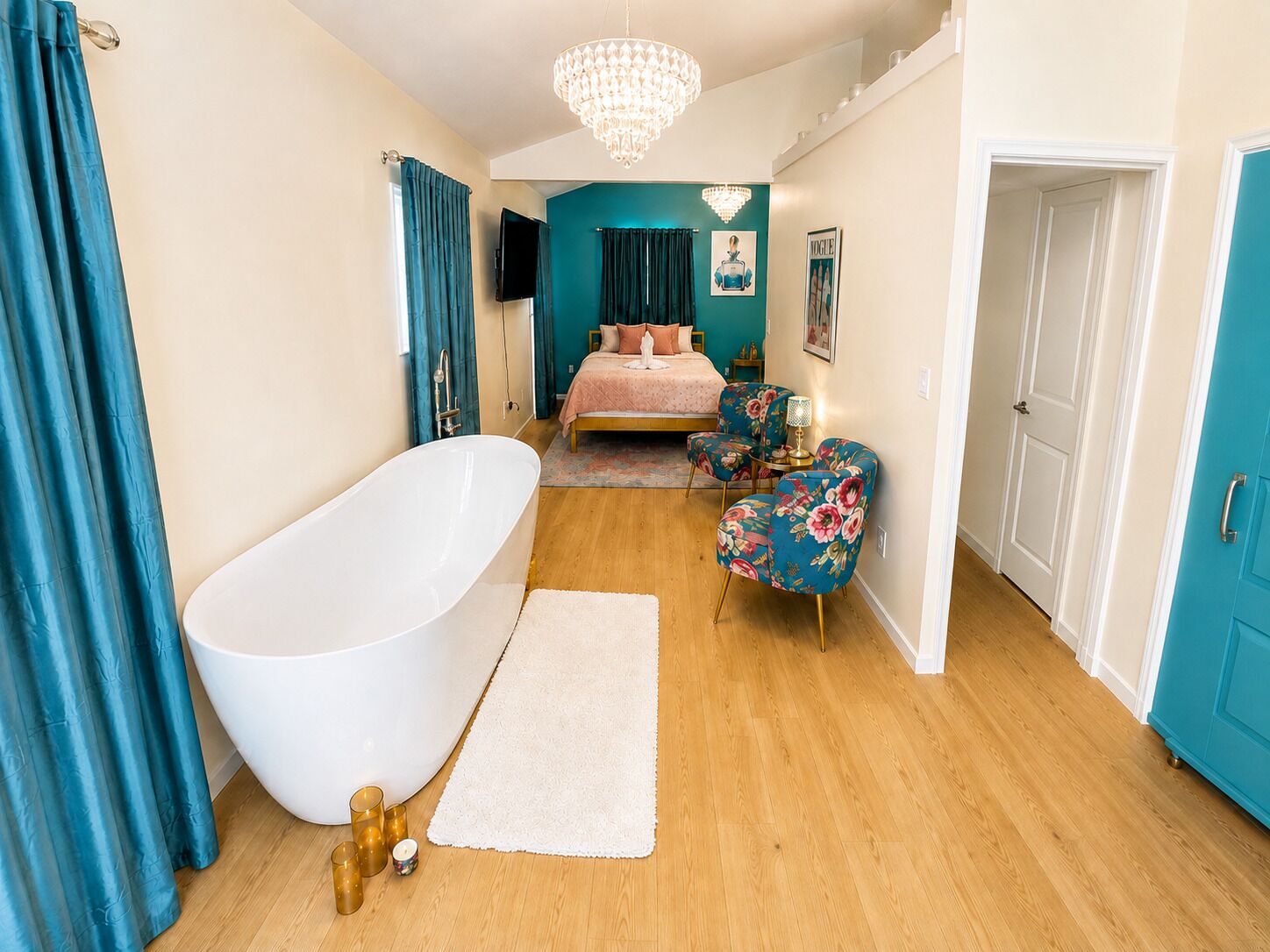 Une chambre avec une grande baignoire blanche, un lit recouvert d’une courtepointe rose et un mur bleu.