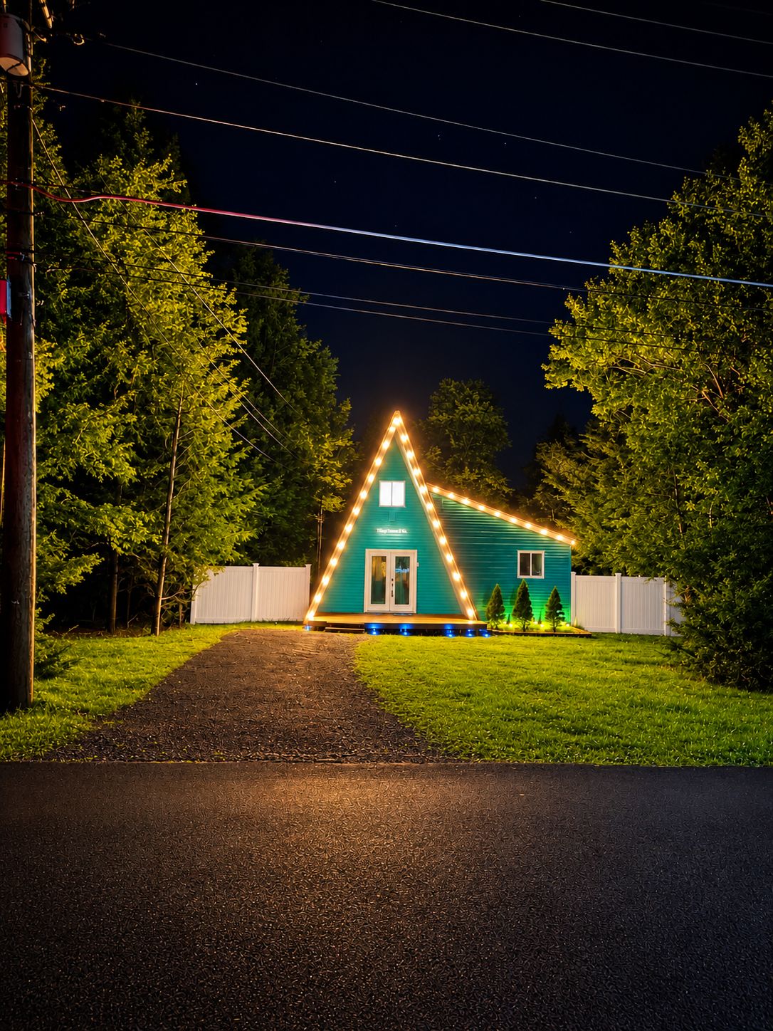 Une maison avec un contour lumineux triangulaire, une porte d’entrée et un petit porche.