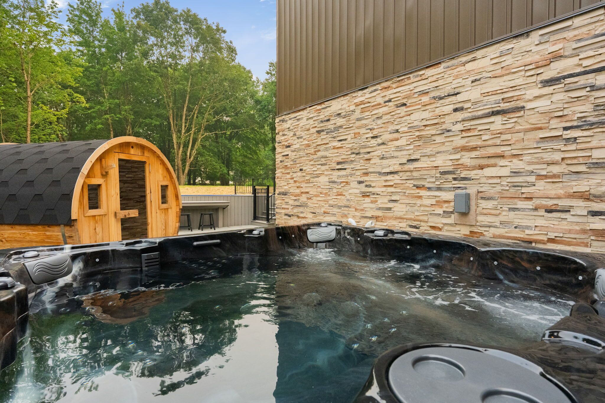 A hot tub area with a stone wall and a wooden structure.