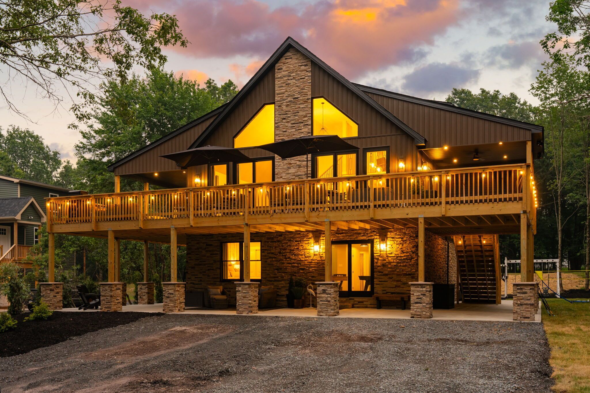 A two-story lodge with a balcony, stone pillars, and a warm interior lighting.