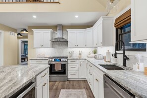 A modern kitchen with white cabinets, a stainless steel range, and a marble countertop. - Pool, Hot Tub, Sauna, Game Room, Luxury and More! (Albrightsville)