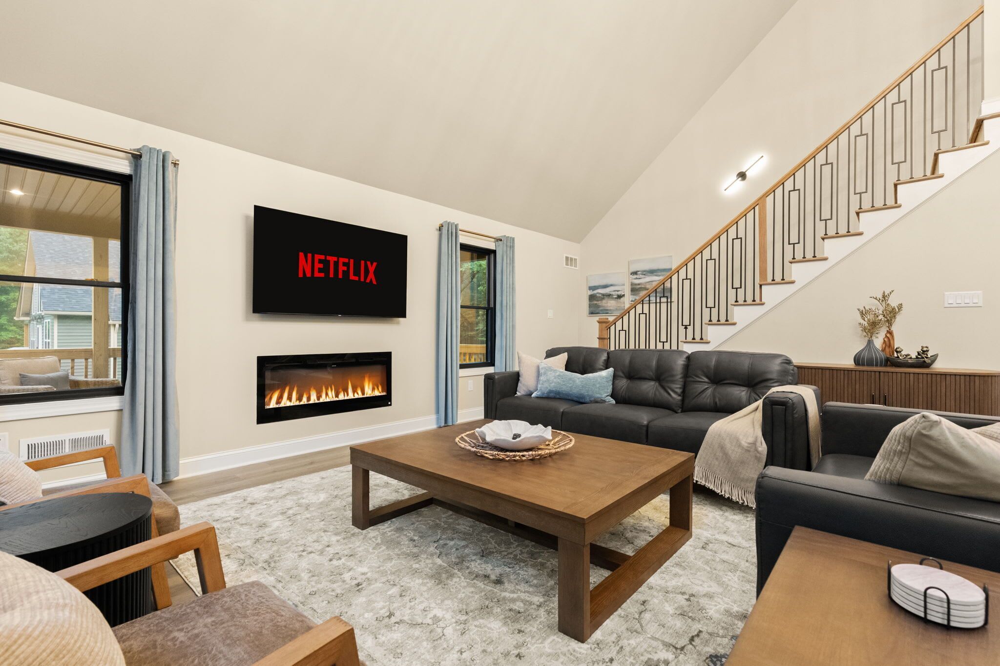 En moderne stue med pejs, trappe og et fladskærms-tv, der viser 'NETFLIX'.