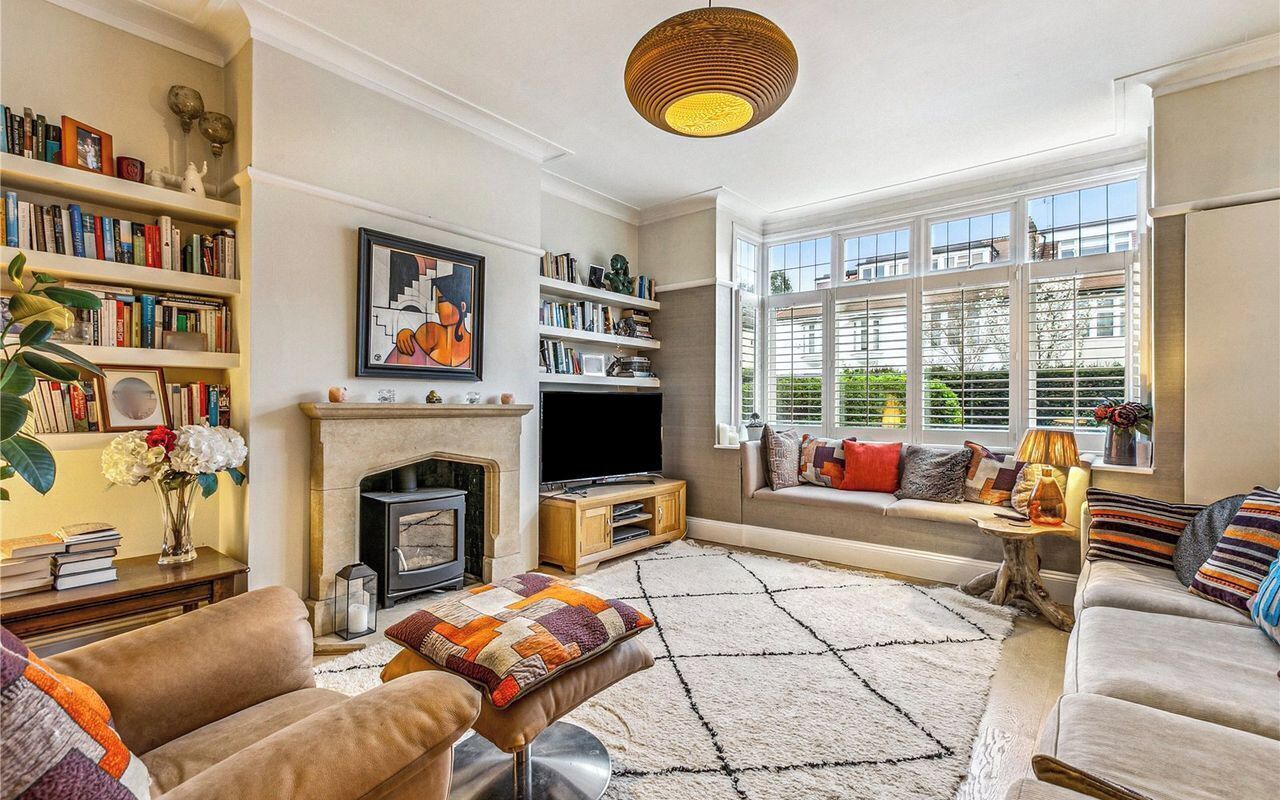 A cozy living room with a fireplace, bookshelves, a sofa, and a large window.