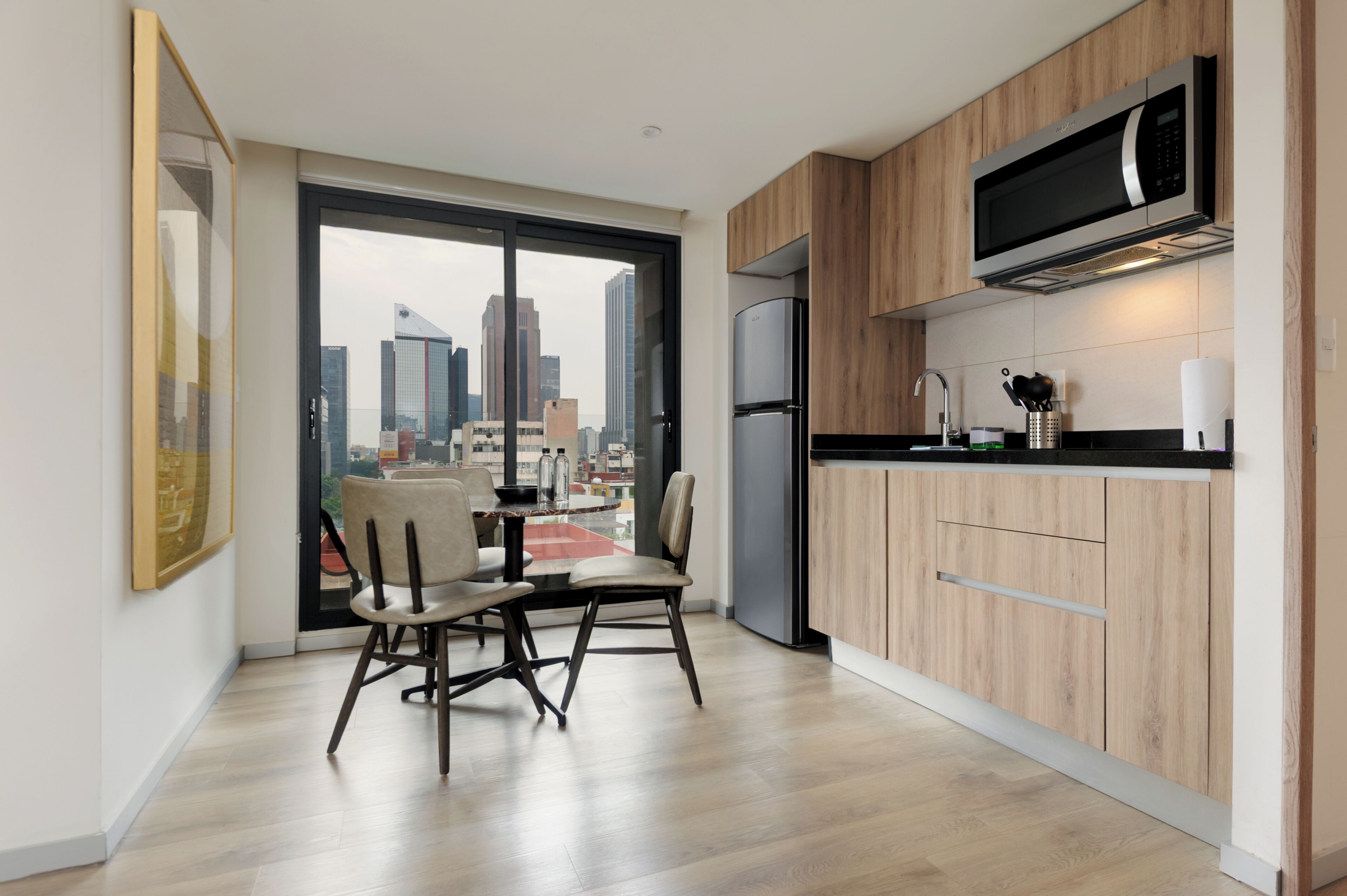 A modern kitchen with a large window, a dining area with two chairs, and a view of the city skyline.