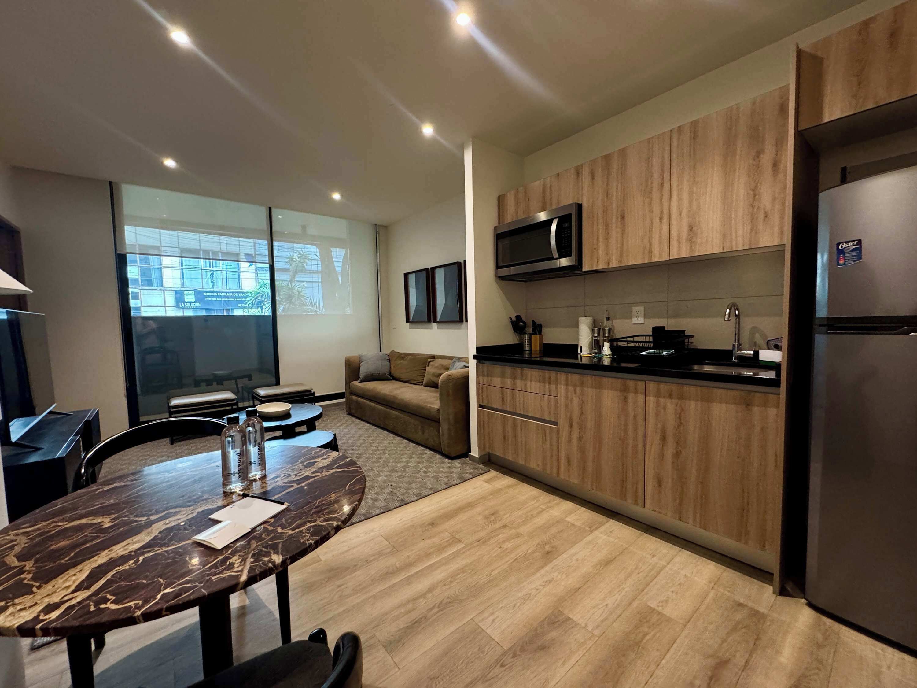 A modern kitchen with wooden cabinets, a built-in microwave, and a refrigerator.
