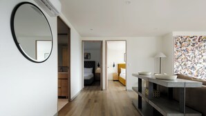 A modern hotel room with a wooden floor, a round mirror, a bed with a headboard, a bedside table with bowls, a sofa, and a lamp. - Rio Nazas 23 by Wynwood House (Ciudad de México)