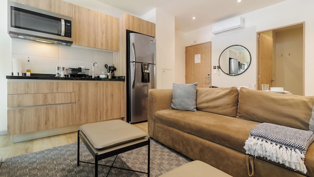 A compact kitchen with modern appliances, a sofa, and a small table. - Rio Nazas 23 by Wynwood House (Ciudad de México)