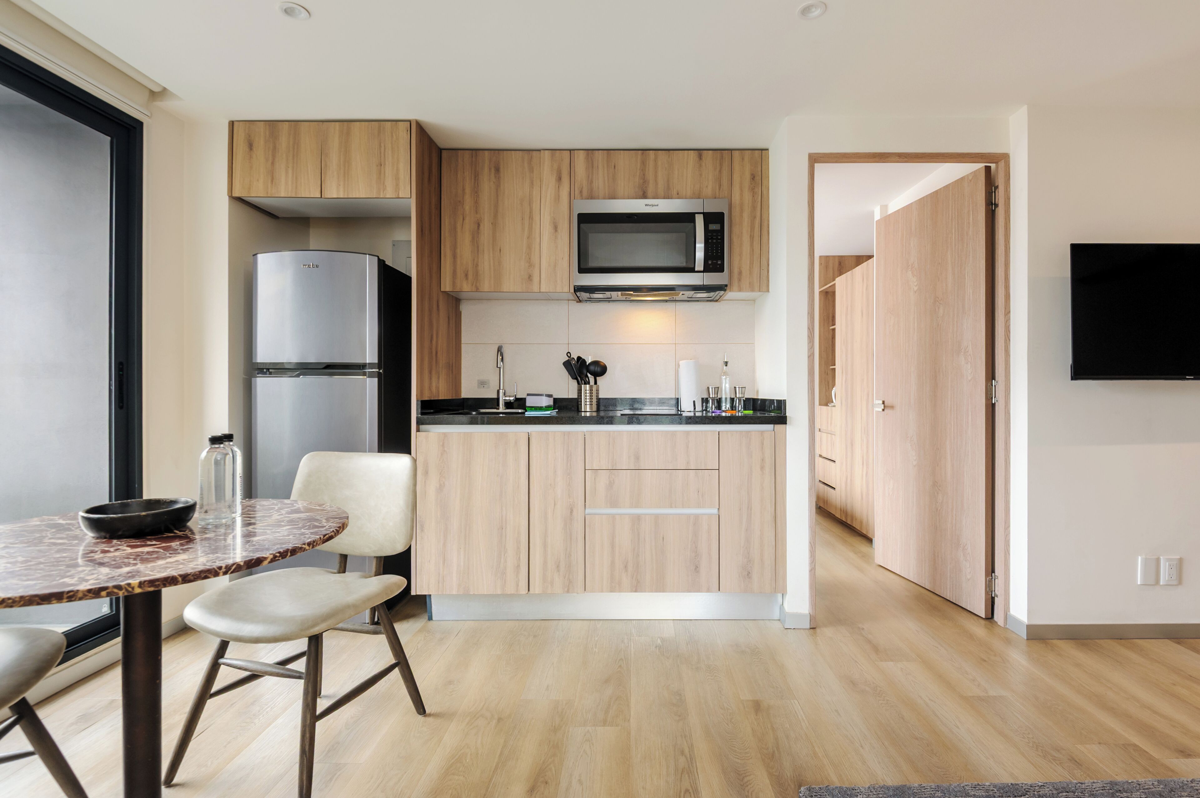 Una cocina moderna con microondas integrado, refrigerador y un comedor con mesa redonda y sillas.