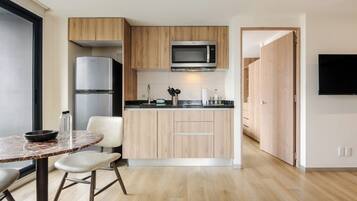 Una cocina moderna con microondas integrado, refrigerador y un comedor con mesa redonda y sillas.