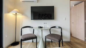 A room with a round table, two chairs, a floor lamp, a flat-screen TV, and a wooden door. - Rio Nazas 23 by Wynwood House (Ciudad de México)