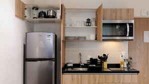 A modern kitchen with a stainless steel refrigerator, a microwave, and wooden cabinets. - Rio Nazas 23 by Wynwood House (Ciudad de México)