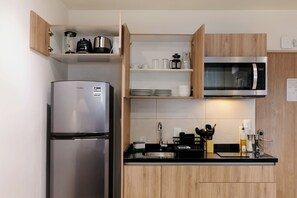 A modern kitchen with a stainless steel refrigerator, a microwave, and wooden cabinets. - Rio Nazas 23 by Wynwood House (Ciudad de México)