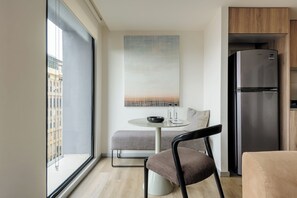 A modern kitchen with a built-in refrigerator, a round dining table with a bench, and a large window offering a view of buildings. - Rio Nazas by Wynwood House (Ciudad de México)