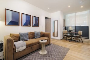 Uma sala de estar moderna com um sofá, uma mesa de centro e uma área de jantar com cadeiras.