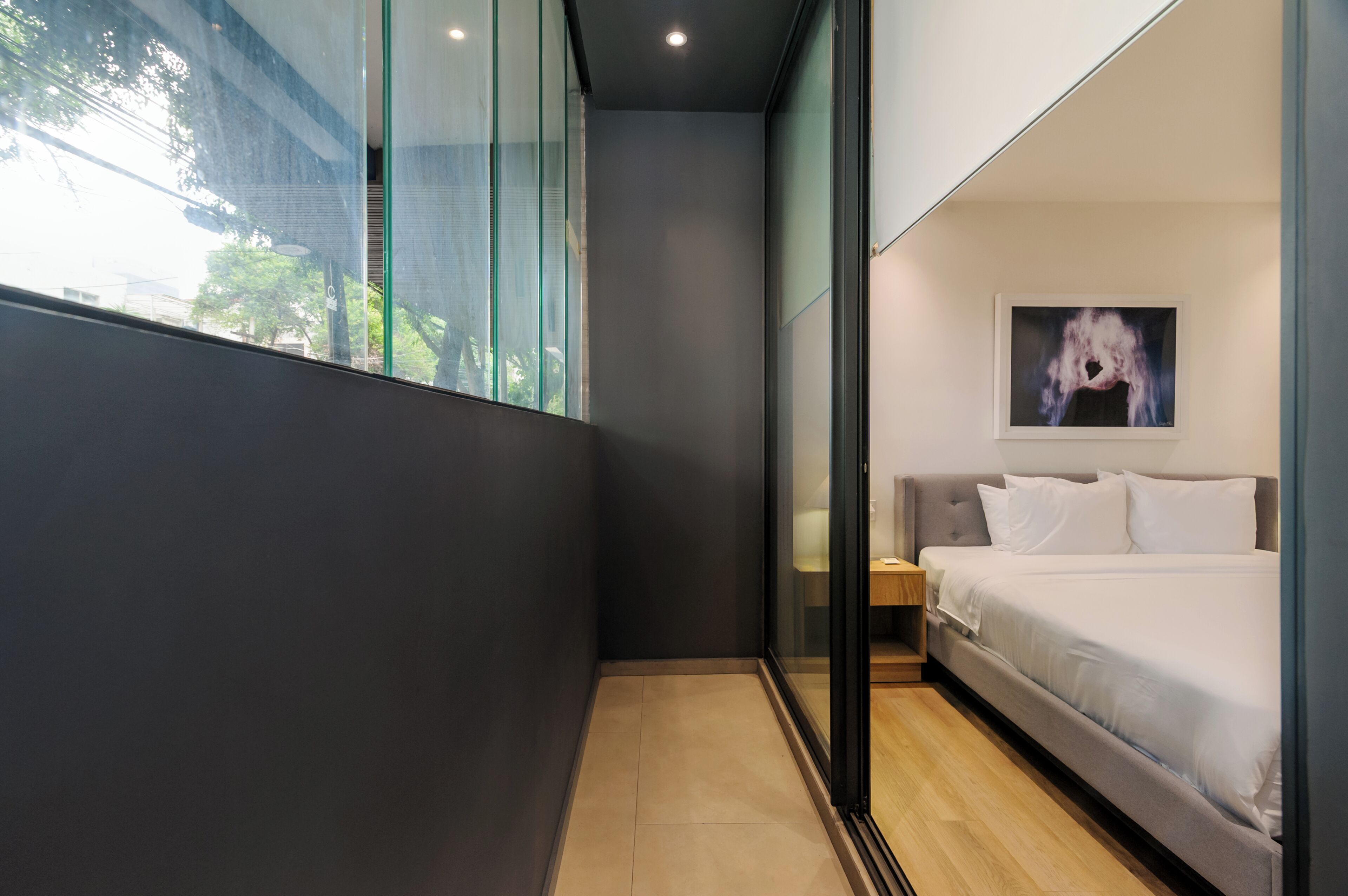 A modern bedroom with a bed, a nightstand, and a painting on the wall.