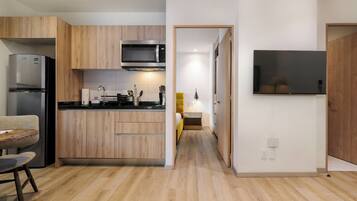 Una cocina moderna con armarios de madera, microondas integrado y un televisor de pantalla plana montado en la pared.