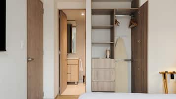 Un dormitorio con cama, armario, espejo y baño con lavabo y toalla.