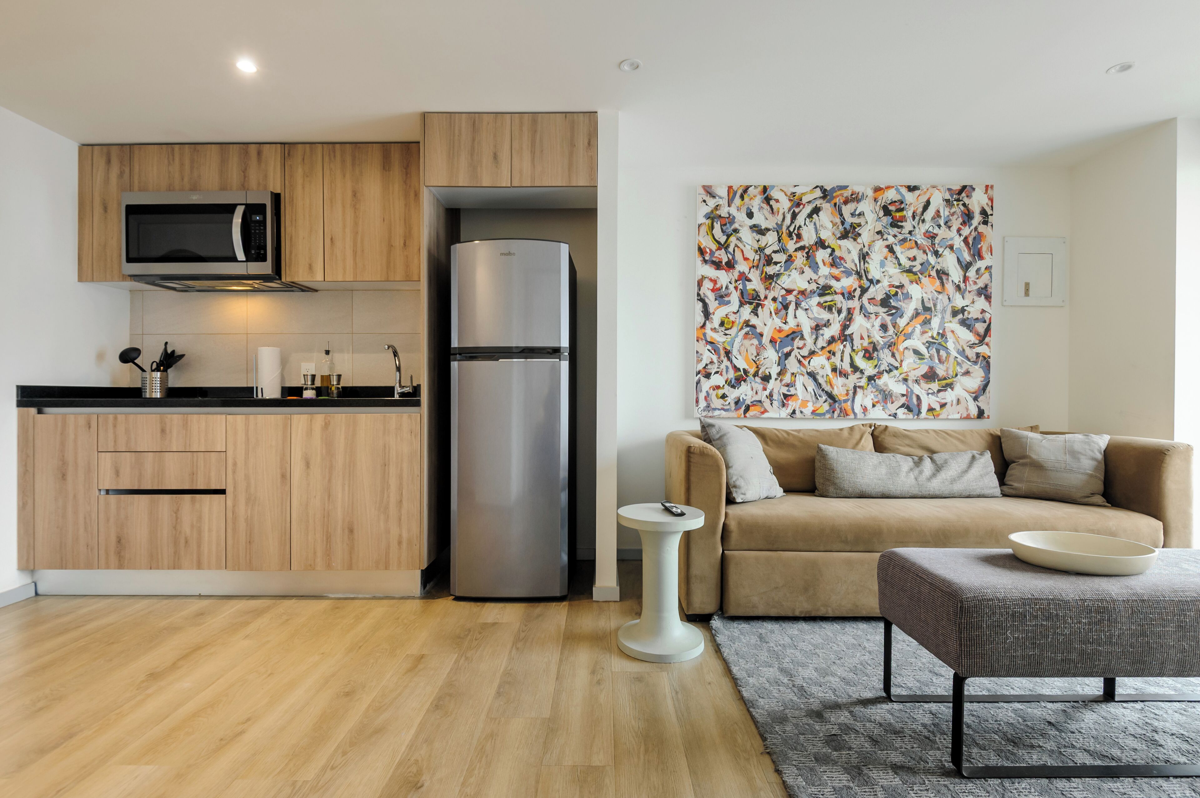 A modern kitchen with wooden cabinets, a stainless steel refrigerator, and a microwave.