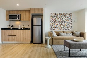 A modern kitchen with wooden cabinets, a stainless steel refrigerator, and a microwave. - Rio Nazas by Wynwood House (Ciudad de México)