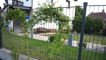 Ein eingezäunter Außenbereich mit einer Bank, einem kleinen Garten und einem Gebäude im Hintergrund.
