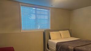 A bedroom with a bed, a window with blinds, a red chair, and a carpeted floor. - Serene 2-bedroom apartment in Tukwila perfect for your stay (Tukwila)