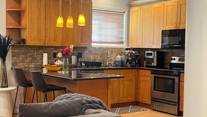 A modern kitchen with wooden cabinets, a central island, stainless steel appliances, and pendant lighting. - Serene 2-bedroom apartment in Tukwila perfect for your stay (Tukwila)