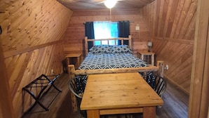 En træhytte med seng, bord og stole.
