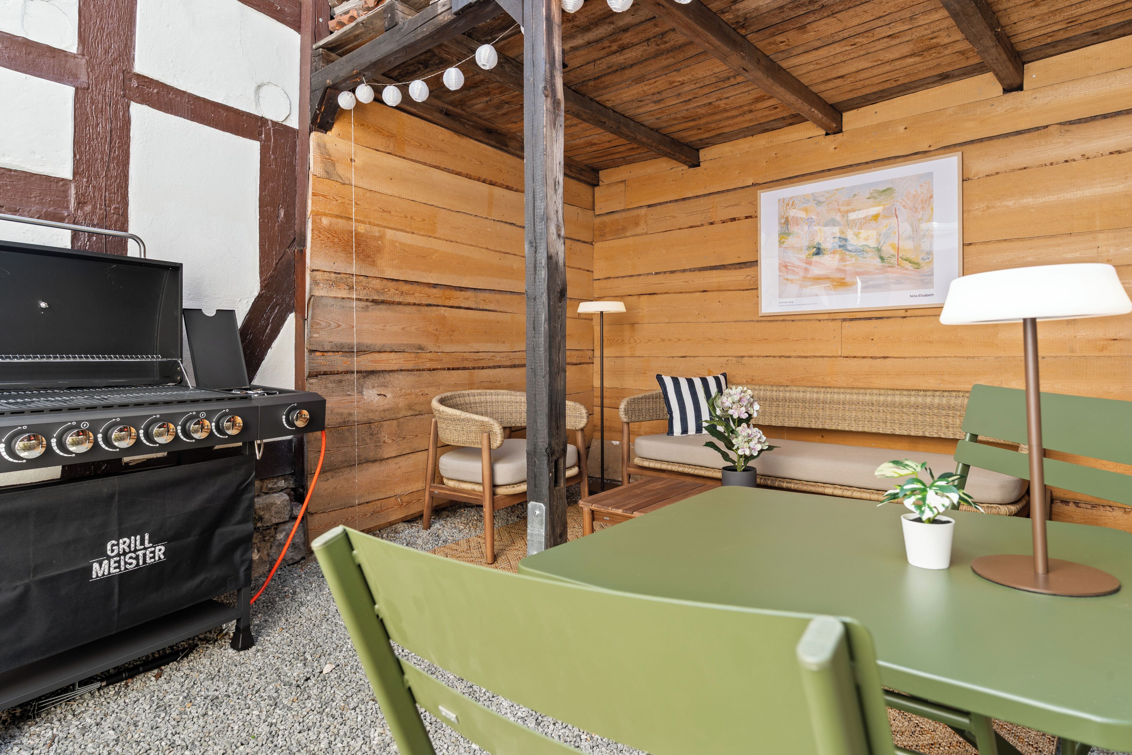 L’intérieur d’un chalet en bois, avec un barbecue, un coin salon et une lampe.