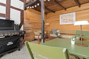 Interior d'una cabana de fusta amb una graella, zona de seients i una làmpada.
