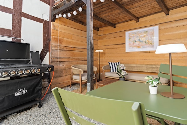 A wooden cabin interior with a grill, seating area, and a lamp. - COUNT'S HOUSE – Historic half-timbered house – Central location, PS5+Switch, BBQ (Korbach)