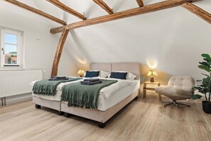 A bedroom with a sloped ceiling, a bed with multiple pillows, a bedside lamp, a chair, and a potted plant. - COUNT'S HOUSE – Historic half-timbered house – Central location, PS5+Switch, BBQ (Korbach)