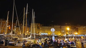 Een jachthaven met boten en een druk waterfront, met gebouwen op de achtergrond.