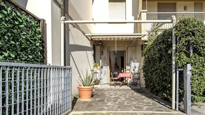 A courtyard with a table and chairs, a potted plant, and a metal fence. - A Tuscan Gem | Family Home with 2 Gardens & Private Parking (Viareggio)