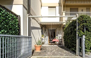 A courtyard with a table and chairs, a potted plant, and a metal fence. - A Tuscan Gem | Family Home with 2 Gardens & Private Parking (Viareggio)