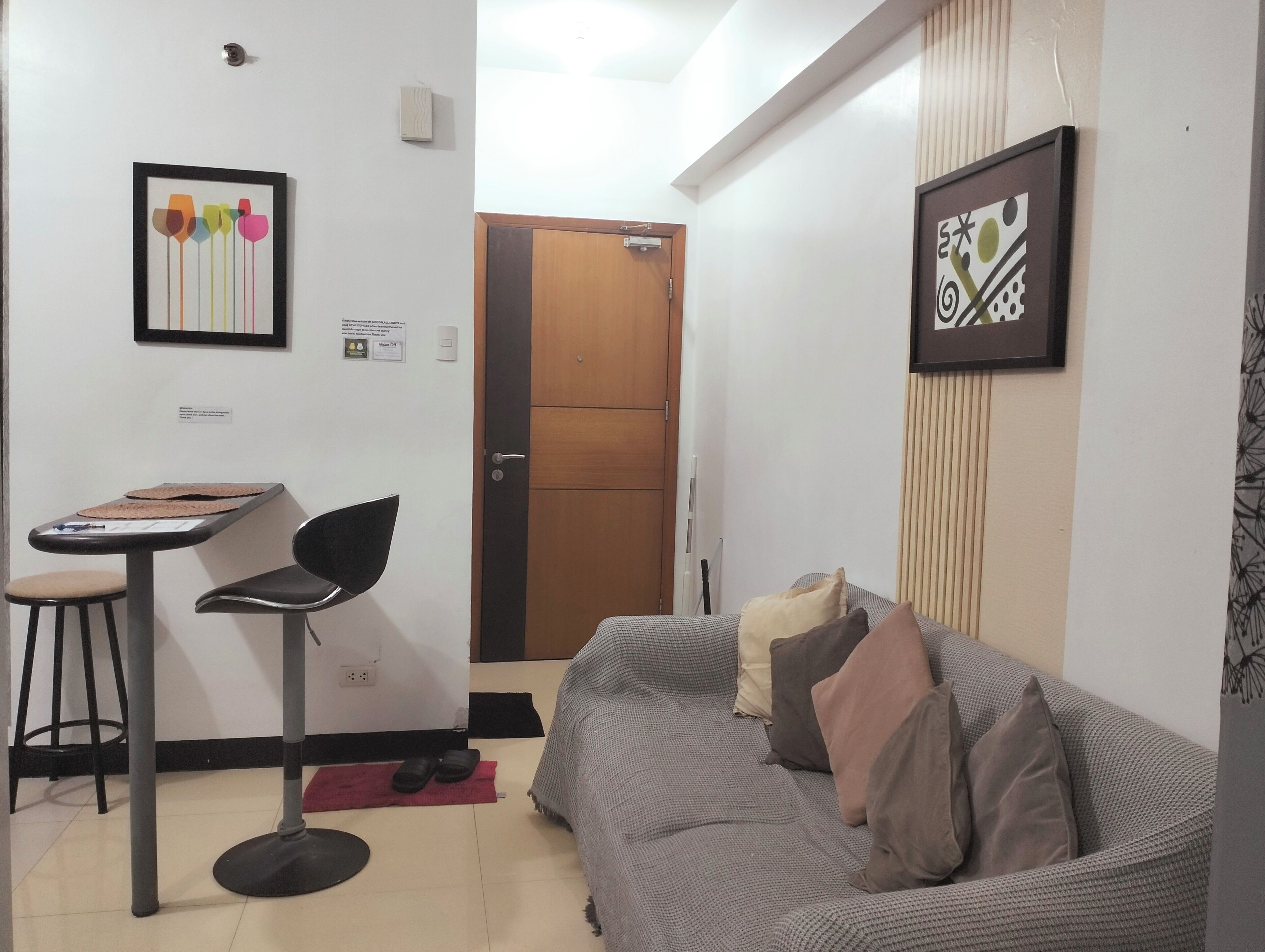 A small, furnished room with a sofa, a chair, a table, and a door leading to another room.