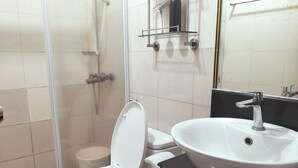 A bathroom with a toilet, a sink, and a shower area.