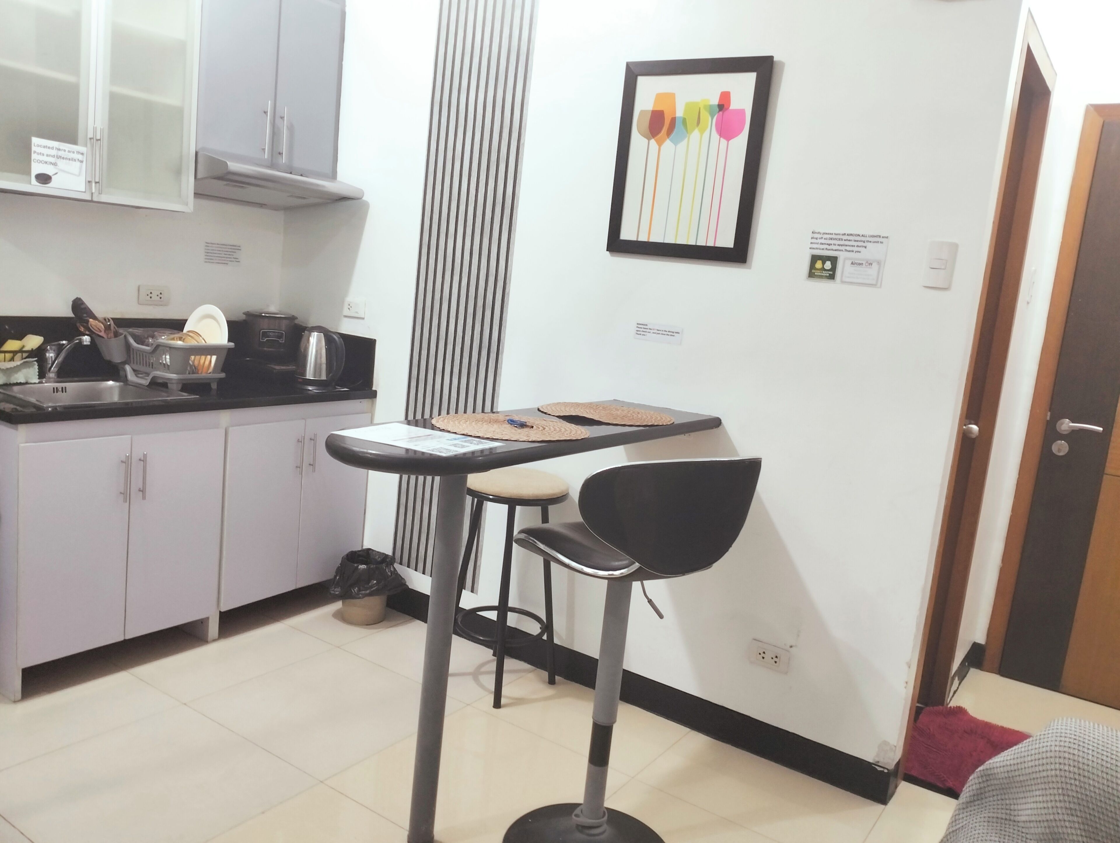 A compact kitchen with a sink, stove, and cabinets. A small dining area with a table and chairs is adjacent to the kitchen.