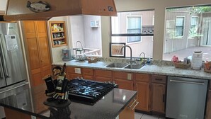 Uma cozinha com fogão embutido, geladeira, pia e armários de madeira.
