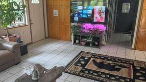 Uma sala de estar com televisão, sofá, mesa de centro e tapete.