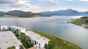 Ein Anwesen am Seeufer mit einer Marina, Gebäuden mit flachen Dächern und Bergen im Hintergrund.