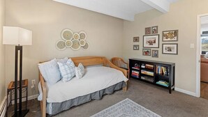 Una camera da letto con un letto, un comodino, una lampada, opere d'arte alle pareti e una libreria.