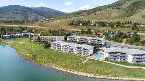 Un resort sul lago con edifici a più piani, una piscina e vista sulle montagne circostanti.