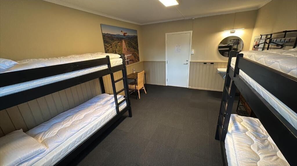 Dormitorio con literas, tres camas dobles, un escritorio, una silla y una puerta.