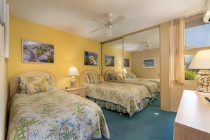 A hotel room with two beds, a ceiling fan, and a large mirror reflecting the room. - Beachfront 4BR, 2 Condos for 12 in Kihei, Hawaii! (Kihei)