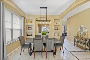A dining area with a table, chairs, and a chandelier. - 7 Bedroom Villa Near Disney World – Pool & Spa, Kissimmee (Kissimmee)